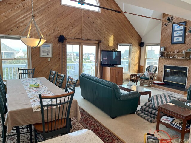 living room featuring wooden walls, high vaulted ceiling, and a fireplace