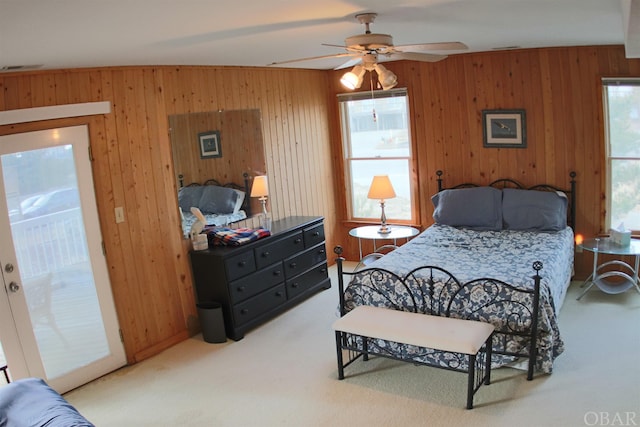 bedroom featuring access to exterior, carpet, wooden walls, and a ceiling fan