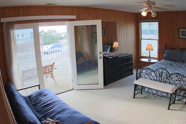 bedroom with access to exterior, carpet flooring, visible vents, and wooden walls