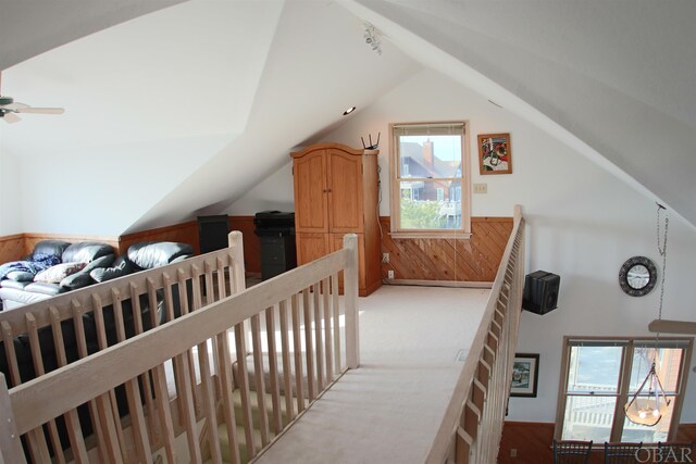 bonus room with light colored carpet, wood walls, a ceiling fan, vaulted ceiling, and wainscoting