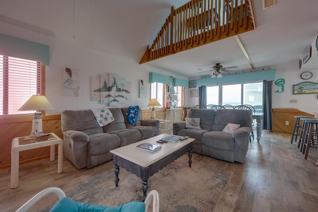 living room featuring wood walls, wainscoting, wood finished floors, and a towering ceiling