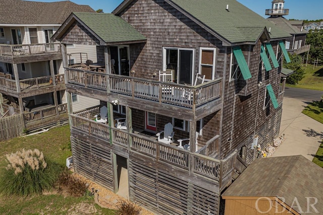 rear view of property with a balcony and roof with shingles