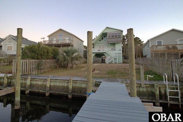 dock area featuring stairway, fence, and a lawn