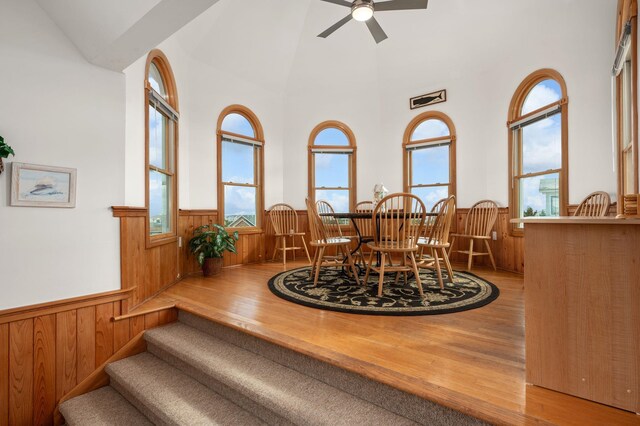 dining area with a wainscoted wall, wood finished floors, and wood walls