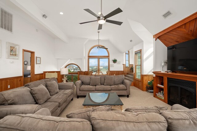 living room with light carpet, wood walls, visible vents, and wainscoting