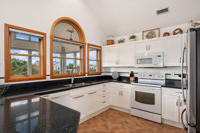 kitchen featuring white appliances, white cabinetry, vaulted ceiling, and a sink