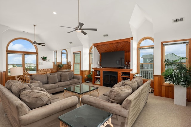 living room featuring light colored carpet, a wainscoted wall, wood walls, and a fireplace