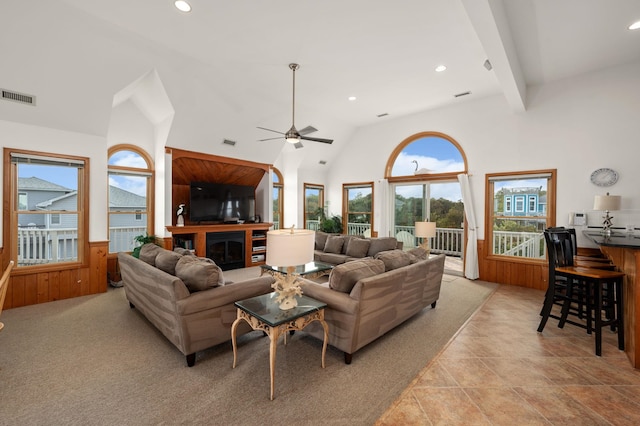 living area with visible vents, a wainscoted wall, beamed ceiling, wood walls, and high vaulted ceiling