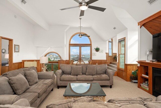 living room with light colored carpet, lofted ceiling with beams, wainscoting, wood walls, and a fireplace