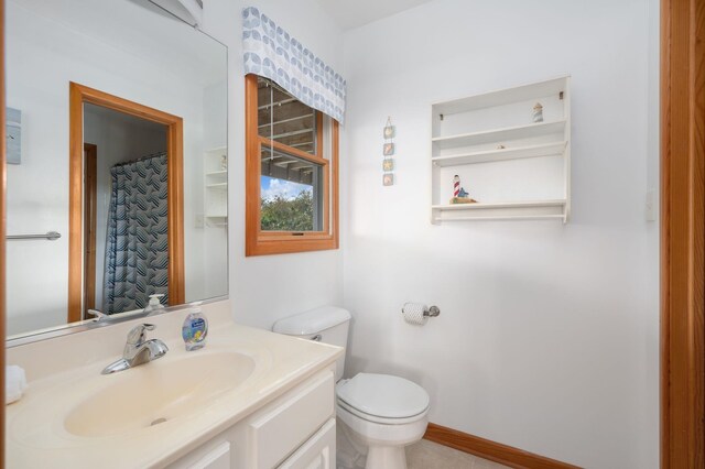 bathroom with toilet, vanity, and baseboards