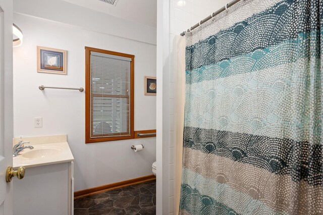 bathroom with toilet, curtained shower, vanity, and baseboards