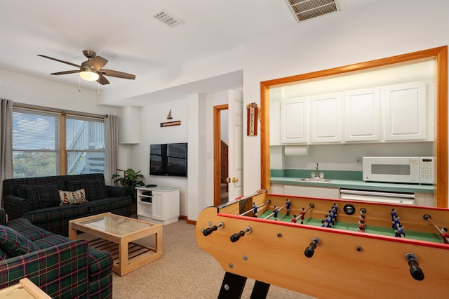 recreation room with light colored carpet, visible vents, a sink, and ceiling fan