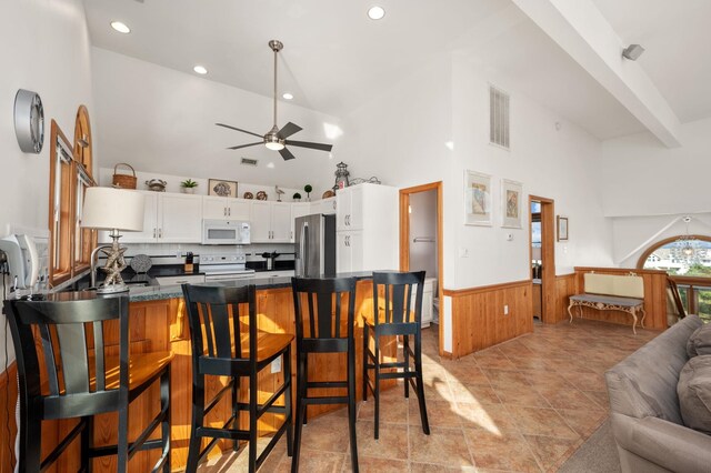 kitchen featuring visible vents, wainscoting, white cabinets, white appliances, and a peninsula