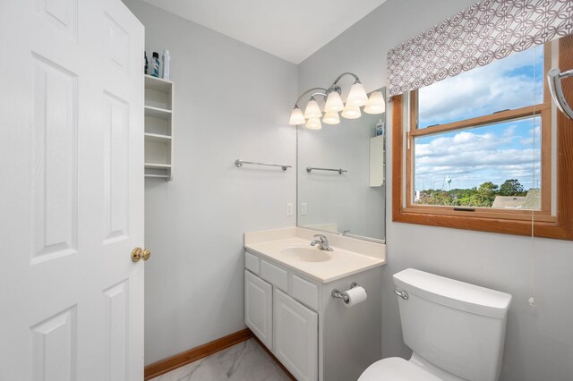 half bath with toilet, marble finish floor, vanity, and baseboards