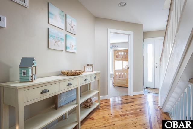 entryway with light wood-style floors, baseboards, and stairway