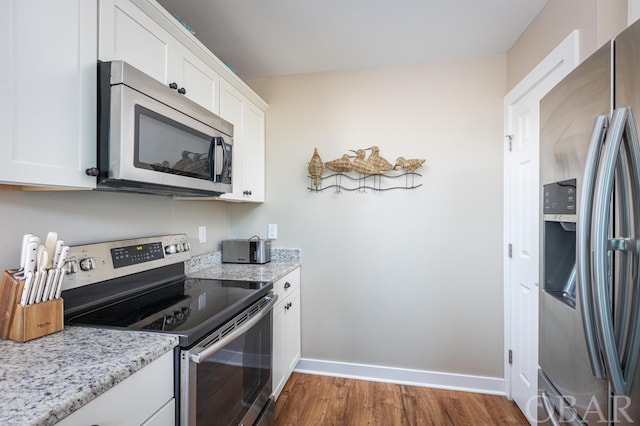 kitchen featuring baseboards, white cabinetry, stainless steel appliances, and light stone counters