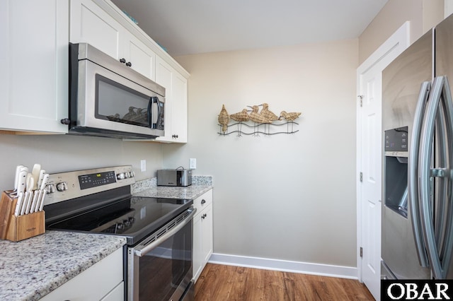 kitchen featuring light stone countertops, baseboards, dark wood-style floors, and appliances with stainless steel finishes