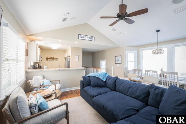living room with wood finished floors, vaulted ceiling, visible vents, and a ceiling fan