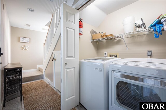 clothes washing area with washing machine and dryer, laundry area, visible vents, and baseboards