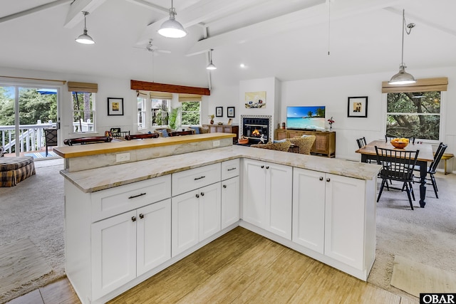 1127 Brumsey Ct Lot 324, Corolla, NC 27927 - kitchen featuring open floor plan, a ceiling fan, a tiled fireplace, light stone counters, and white cabinets
