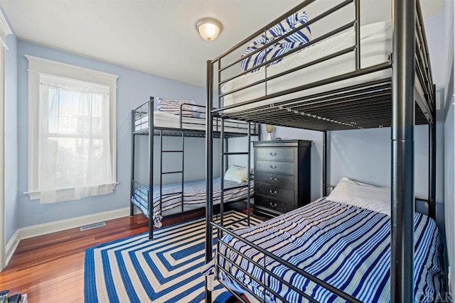 bedroom with wood finished floors, visible vents, and baseboards