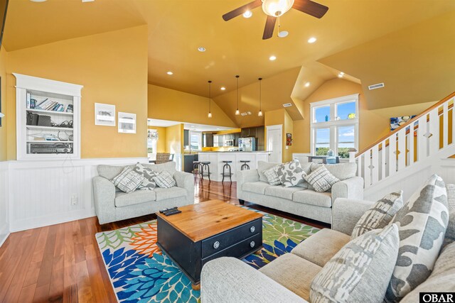 living room featuring lofted ceiling, recessed lighting, wood finished floors, visible vents, and stairway