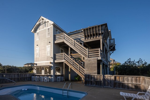 view of swimming pool featuring a fenced in pool, a patio, outdoor dry bar, stairs, and fence