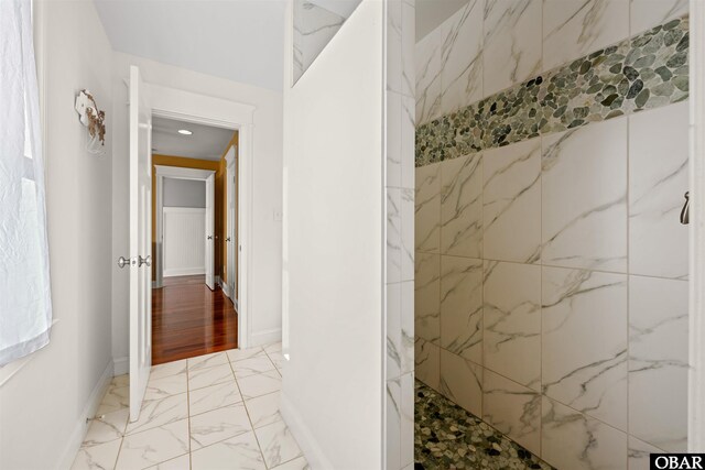 bathroom featuring marble finish floor, baseboards, and walk in shower