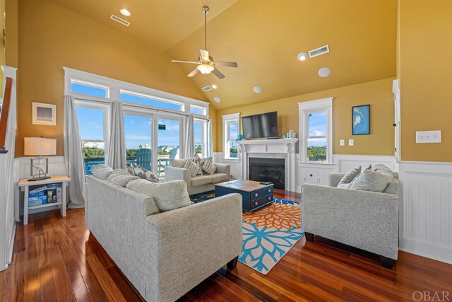 living room featuring a wainscoted wall, a fireplace, dark wood finished floors, and visible vents