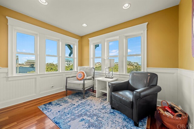 living area with recessed lighting, a wainscoted wall, and wood finished floors