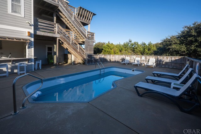 view of swimming pool featuring a fenced in pool, a patio, stairway, exterior bar, and a fenced backyard