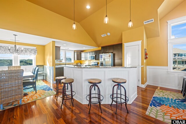 kitchen featuring a wainscoted wall, stainless steel appliances, dark wood-style floors, and visible vents