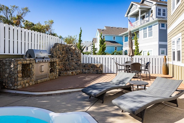 view of patio / terrace featuring grilling area, fence, a deck, exterior kitchen, and a residential view