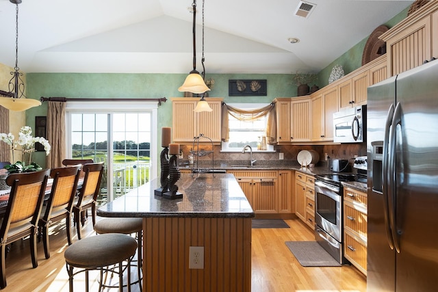 kitchen with appliances with stainless steel finishes, dark countertops, pendant lighting, and visible vents