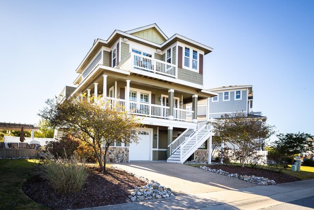 view of front of home featuring an attached garage, covered porch, stairs, concrete driveway, and board and batten siding