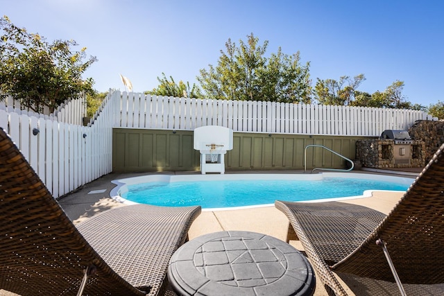 view of pool featuring a fenced in pool, a fenced backyard, a patio, and an outdoor kitchen