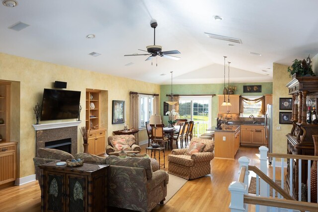 living area featuring vaulted ceiling, visible vents, a fireplace, and light wood-style flooring