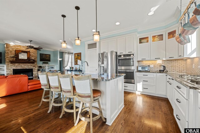 kitchen featuring light stone countertops, a breakfast bar, ornamental molding, a stone fireplace, and stainless steel appliances