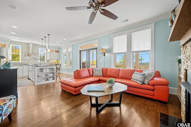 living room featuring visible vents, ornamental molding, light wood-style floors, a fireplace, and baseboards