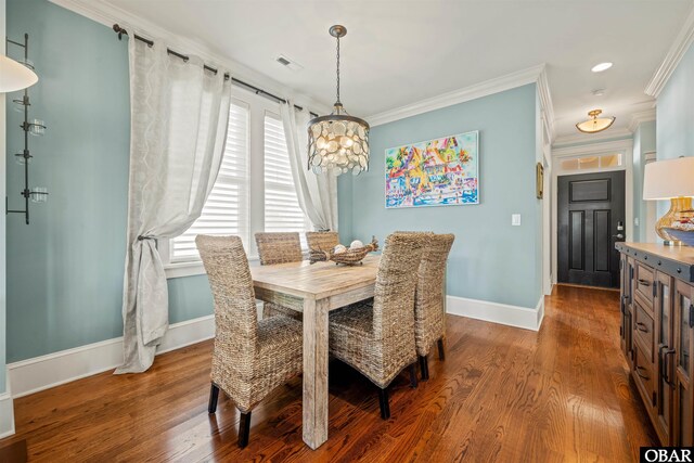 dining room featuring wood finished floors, visible vents, baseboards, an inviting chandelier, and crown molding