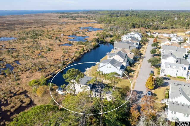 aerial view with a wooded view, a residential view, and a water view