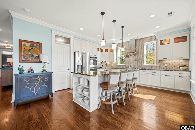 kitchen featuring glass insert cabinets, a center island with sink, a kitchen breakfast bar, white cabinets, and open shelves