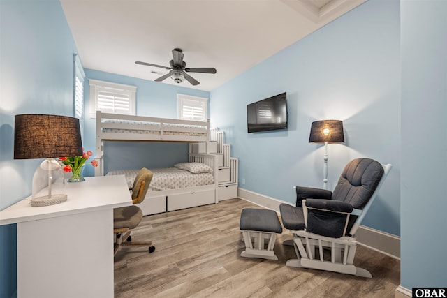 bedroom featuring baseboards, wood finished floors, and a ceiling fan