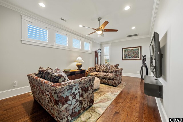 living room with visible vents, baseboards, dark wood-type flooring, and crown molding