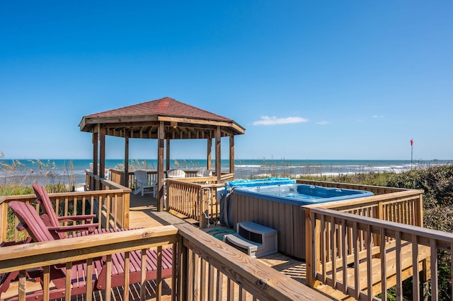 wooden terrace featuring a water view, a hot tub, and a gazebo