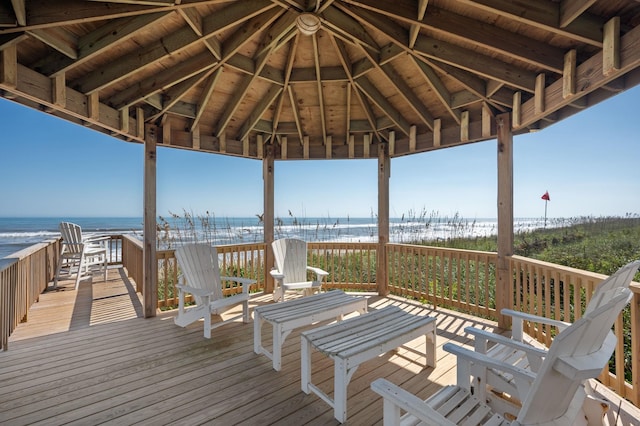 wooden terrace featuring a water view, a view of the beach, and a gazebo