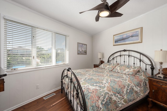 bedroom with dark wood-style flooring, visible vents, crown molding, and ceiling fan