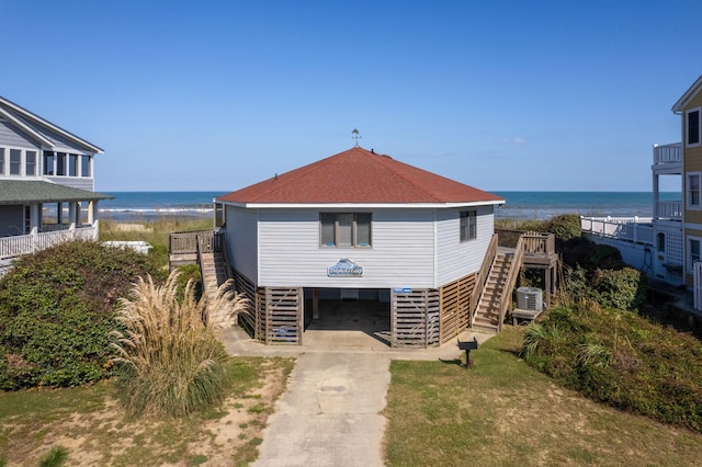 view of front of property featuring concrete driveway, a water view, a carport, stairs, and central AC