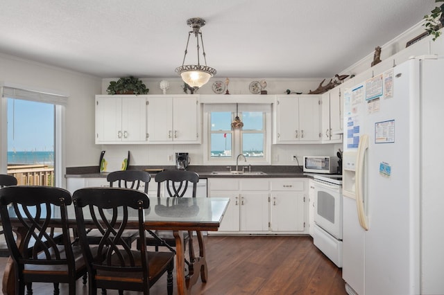 kitchen featuring dark countertops, white appliances, white cabinets, and a sink