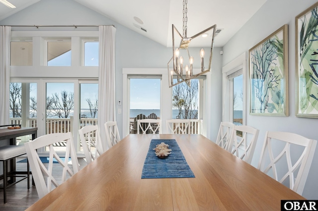 dining area featuring high vaulted ceiling, wood finished floors, and an inviting chandelier